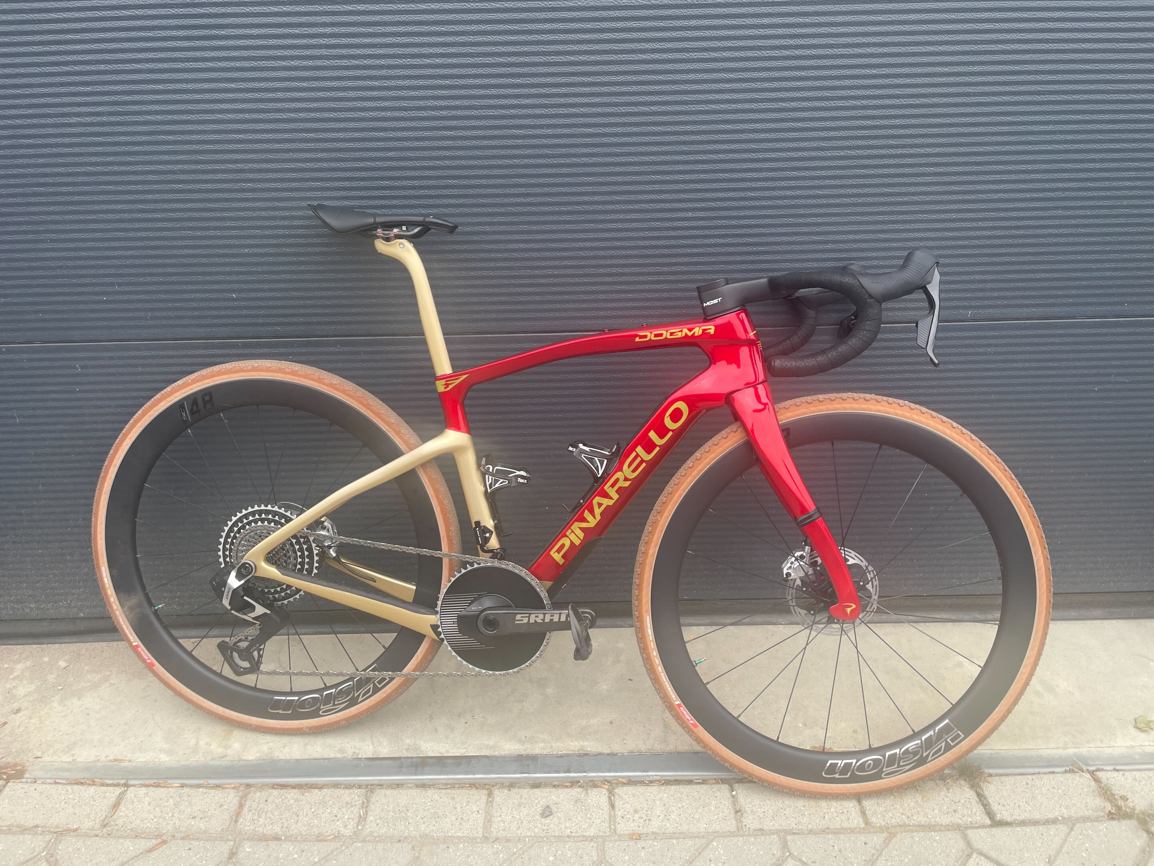 Tom Pidcock&#039;s Dogma GR gravel bike, in red and gold, leaning against a wall