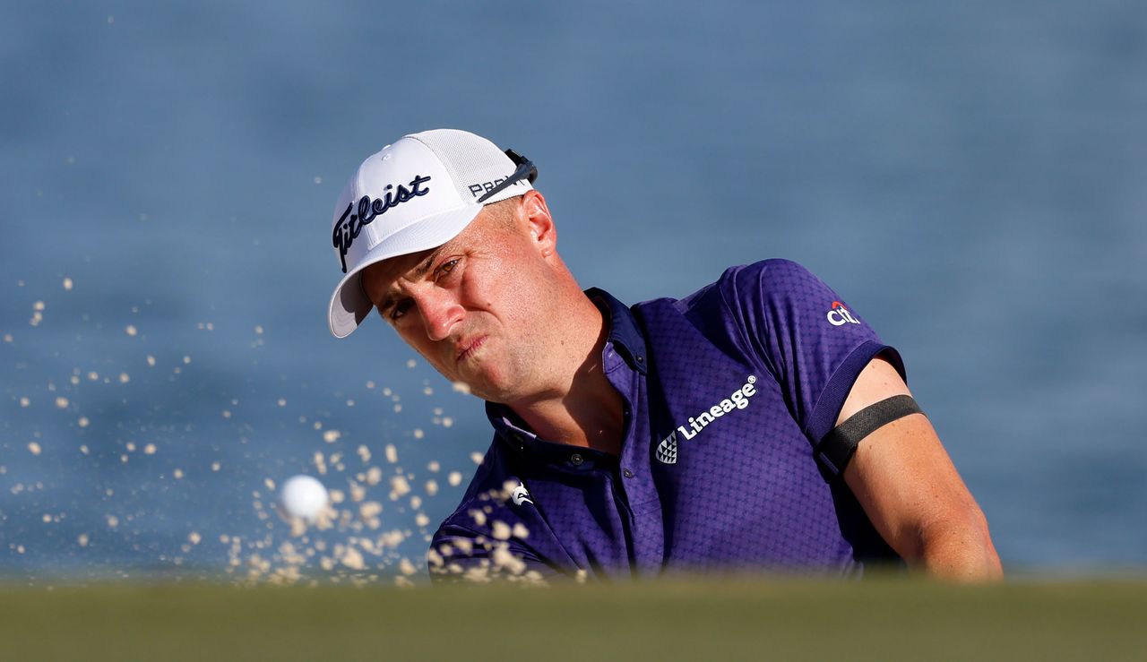 Justin Thomas hits a bunker shot and watches its flight