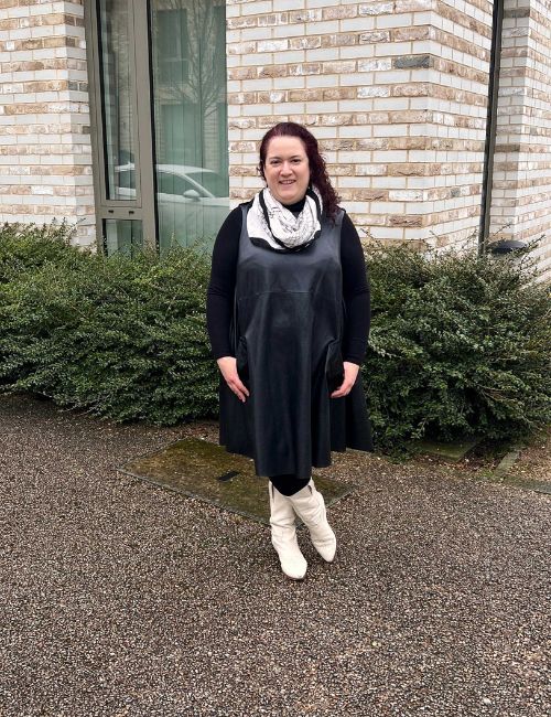 Rivkie Baum in a black leather dress and white boots