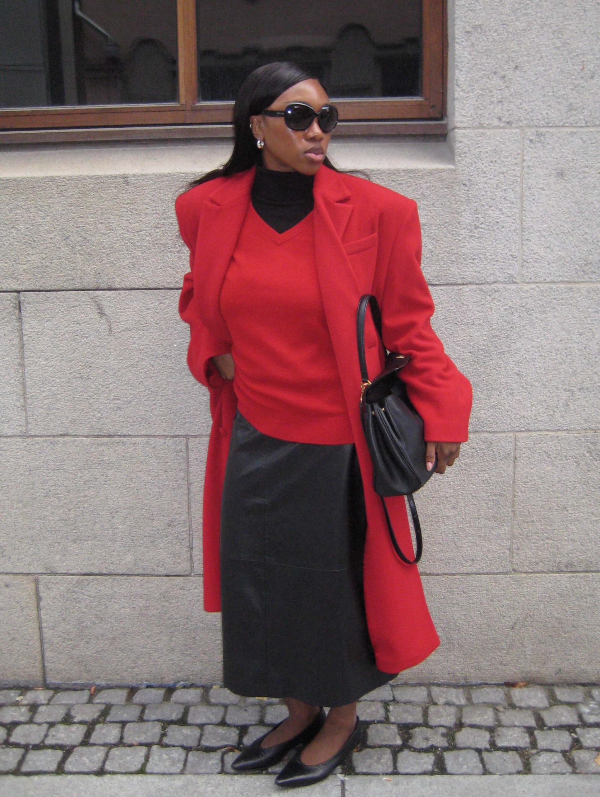 @nnennaechem wears a red coat and jumper and a black skirt
