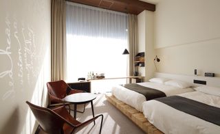 hotel guest bedroom with 2 double beds raised on wooden bases and neutral decor