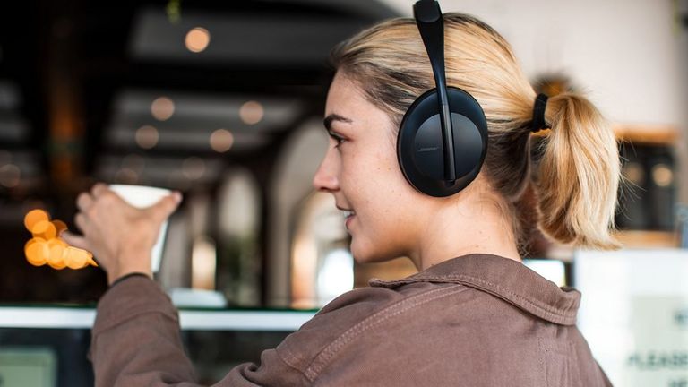 Best headphones with mic 2021, Bose Noise Cancelling Headphones 700 worn by woman buying coffee