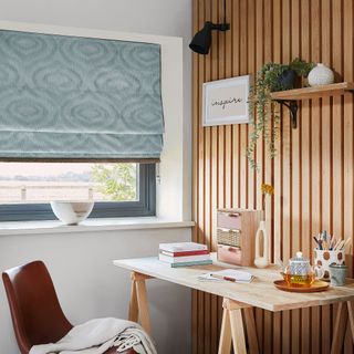Home office with wood panelled walls and blue roman blind over window