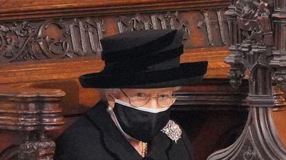 WINDSOR, ENGLAND - APRIL 17: Queen Elizabeth II takes her seat during the funeral of Prince Philip, Duke of Edinburgh, at St George's Chapel at Windsor Castle on April 17, 2021 in Windsor, England. Prince Philip of Greece and Denmark was born 10 June 1921, in Greece. He served in the British Royal Navy and fought in WWII. He married the then Princess Elizabeth on 20 November 1947 and was created Duke of Edinburgh, Earl of Merioneth, and Baron Greenwich by King VI. He served as Prince Consort to Queen Elizabeth II until his death on April 9 2021, months short of his 100th birthday. His funeral takes place today at Windsor Castle with only 30 guests invited due to Coronavirus pandemic restrictions. (Photo by Jonathan Brady - WPA Pool/Getty Images)
