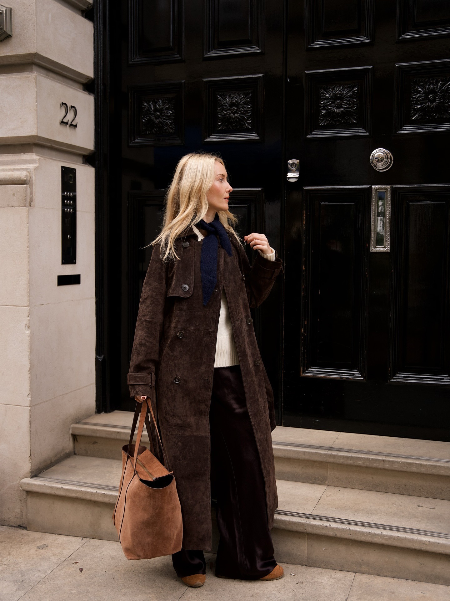Woman wears brown suede trench coat, cream knit, cashmere scarf and brown shoes