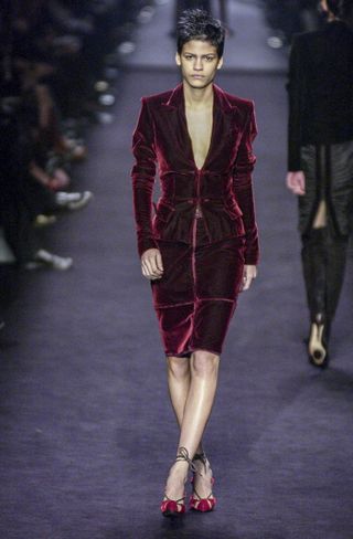 a model walks the saint laurent runway wearing a crimson velvet suit