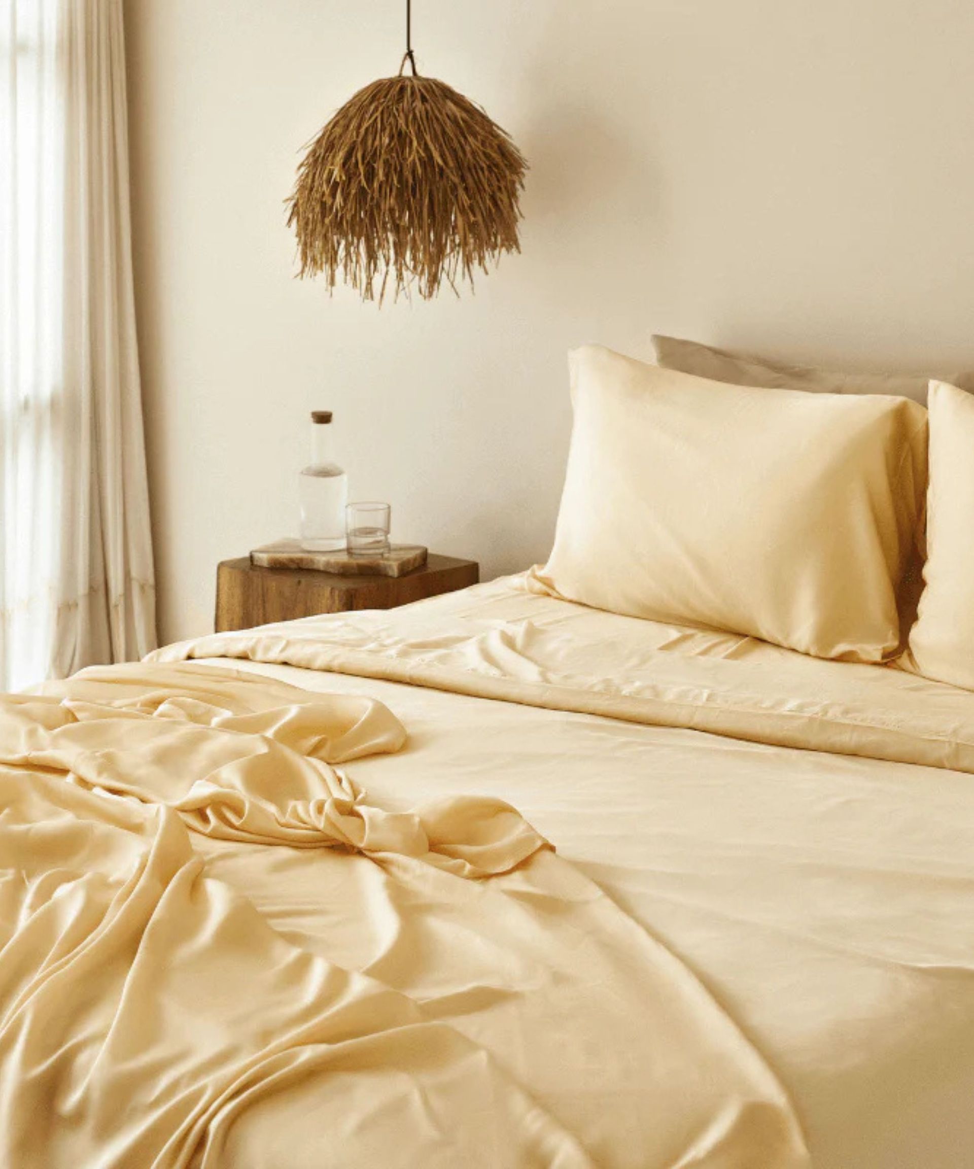 Yellow sheets on a bed against cream walls.