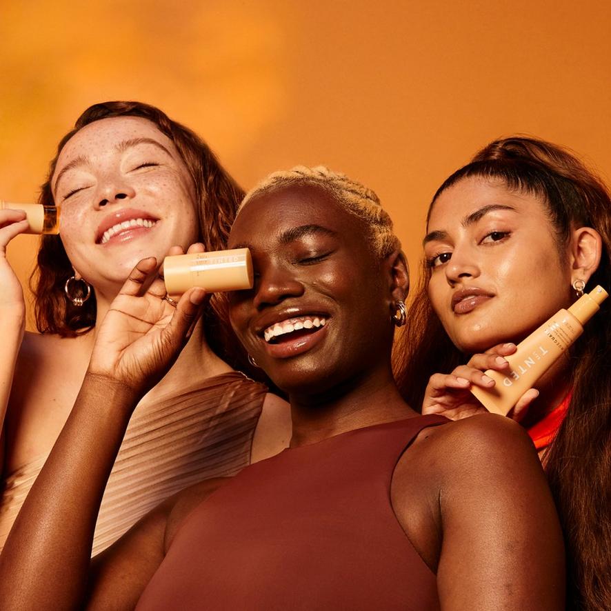 three women holding Live Tinted products