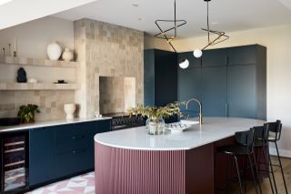A kitchen with pink island and blue cabinets