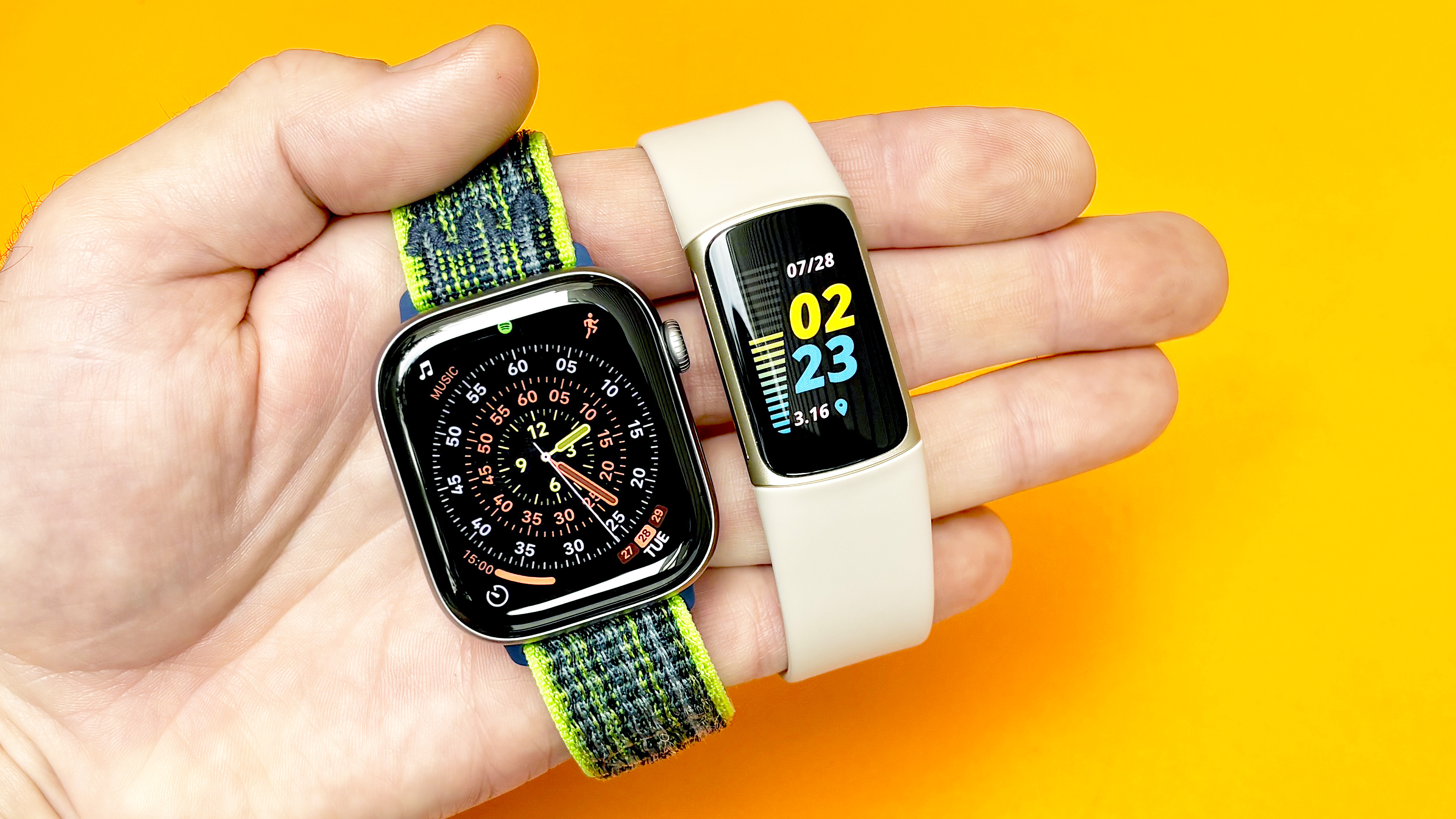 Close-up of the Fitbit Charge 5 next to the Apple Watch Series 11
