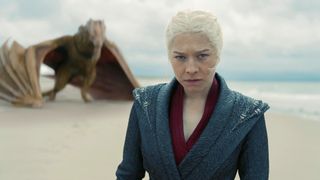 Rhaenyra (Emm D&#039;Arcy) stands on a beach with her dragon, Syrax, in the background in &quot;House of the Dragon&quot; season 2