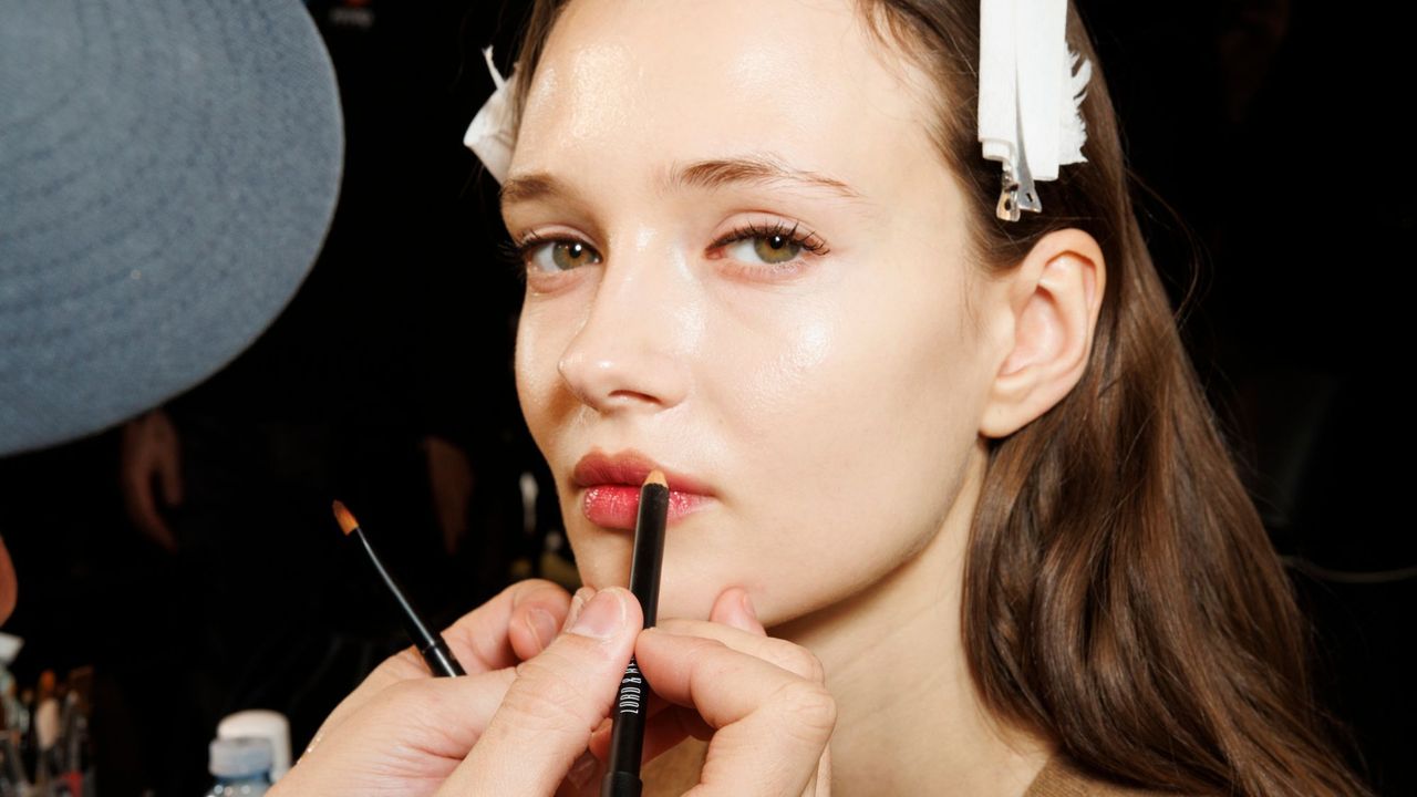 Make-up artist applying lip liner to model&#039;s lips