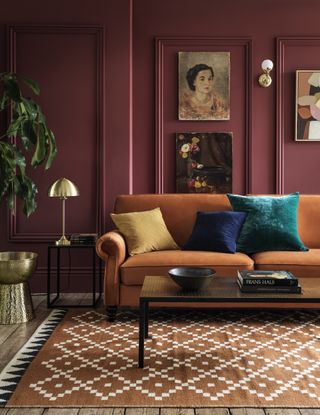 fall coloured living room with orange rug, burgundy walls and orange rug