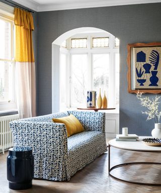 A living room with blue wallpaper and yellow accents