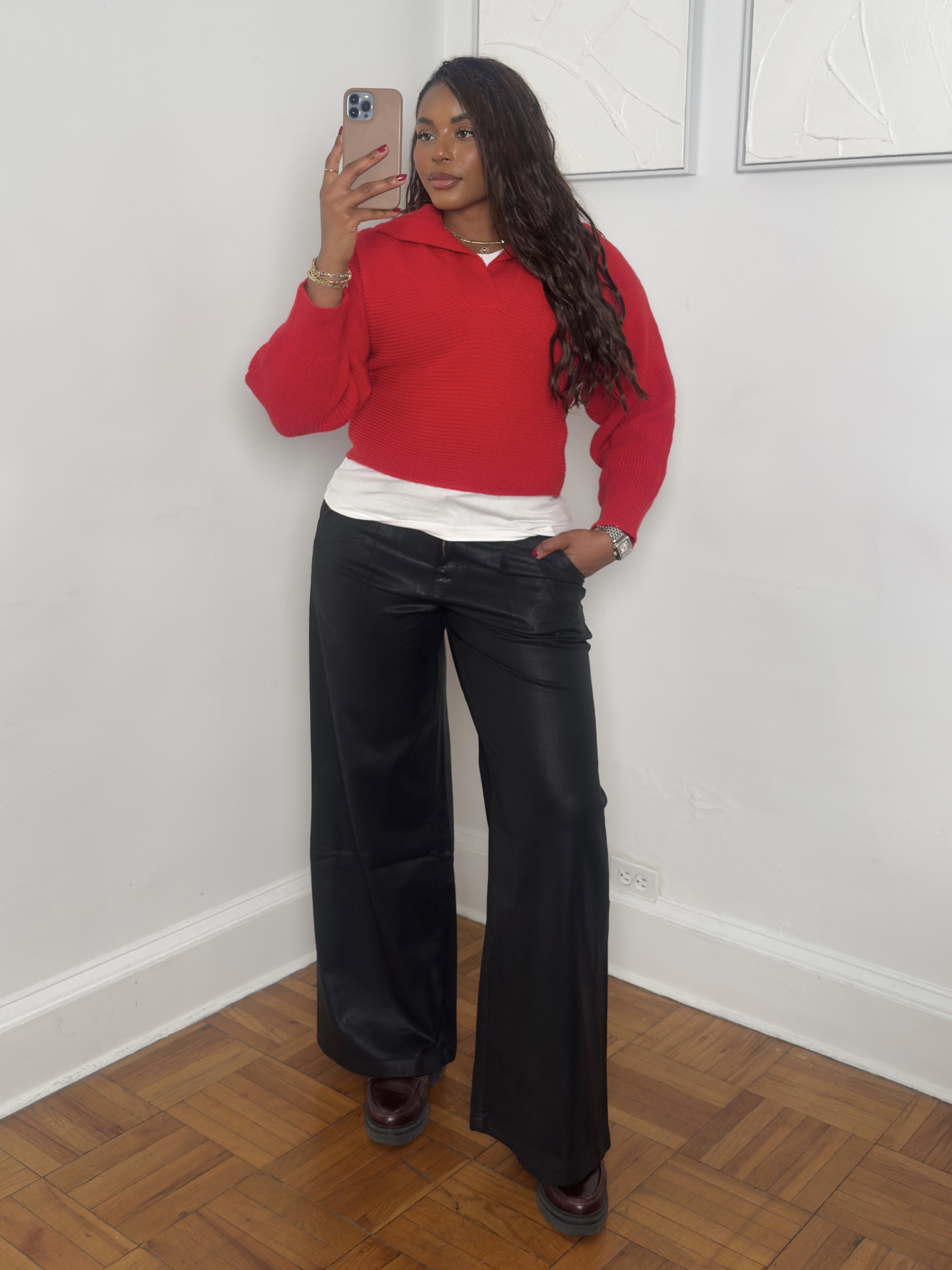 fashion and beauty influencer Kaye Bassey poses in a winter 2026 outfit formula with a red sweater, white T-shirt, and black leather pants