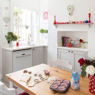 Stylish white kitchen with dough rolled out and cupcake tray on wooden table