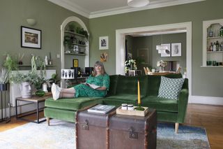 Green living room with green velvet sofa, dark wood storage chest/coffee table,