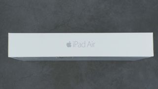 Box containing silver Apple iPad Air 2, 6th generation of the iPad, on grey background