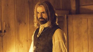 Richard Warren standing in a cabin room that's lit by candlelight in Widow's Bay episode 6