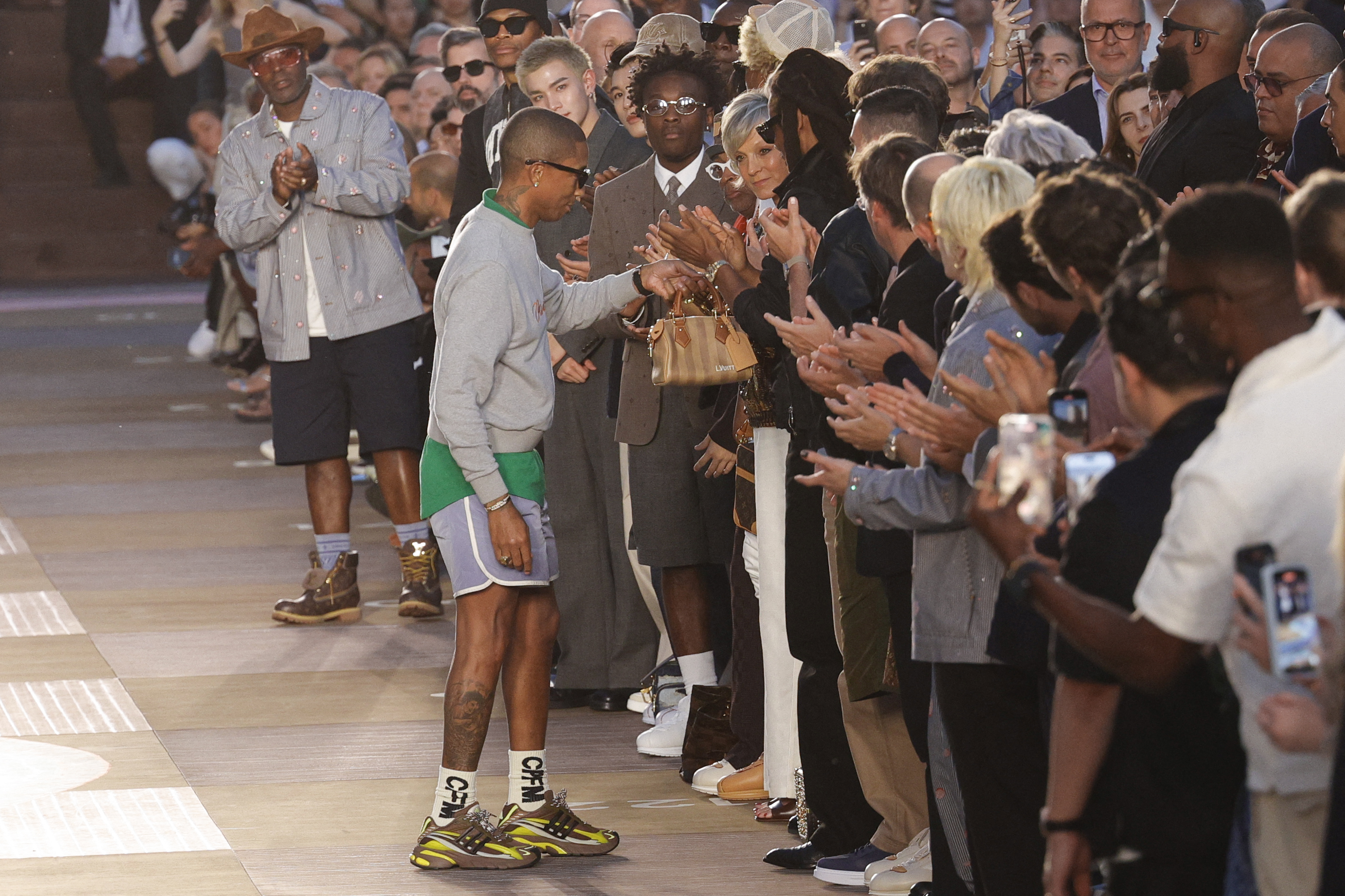 Pharrell Williams gifts Beyoncé a Spring 2026 bag at the Louis Vuitton show.