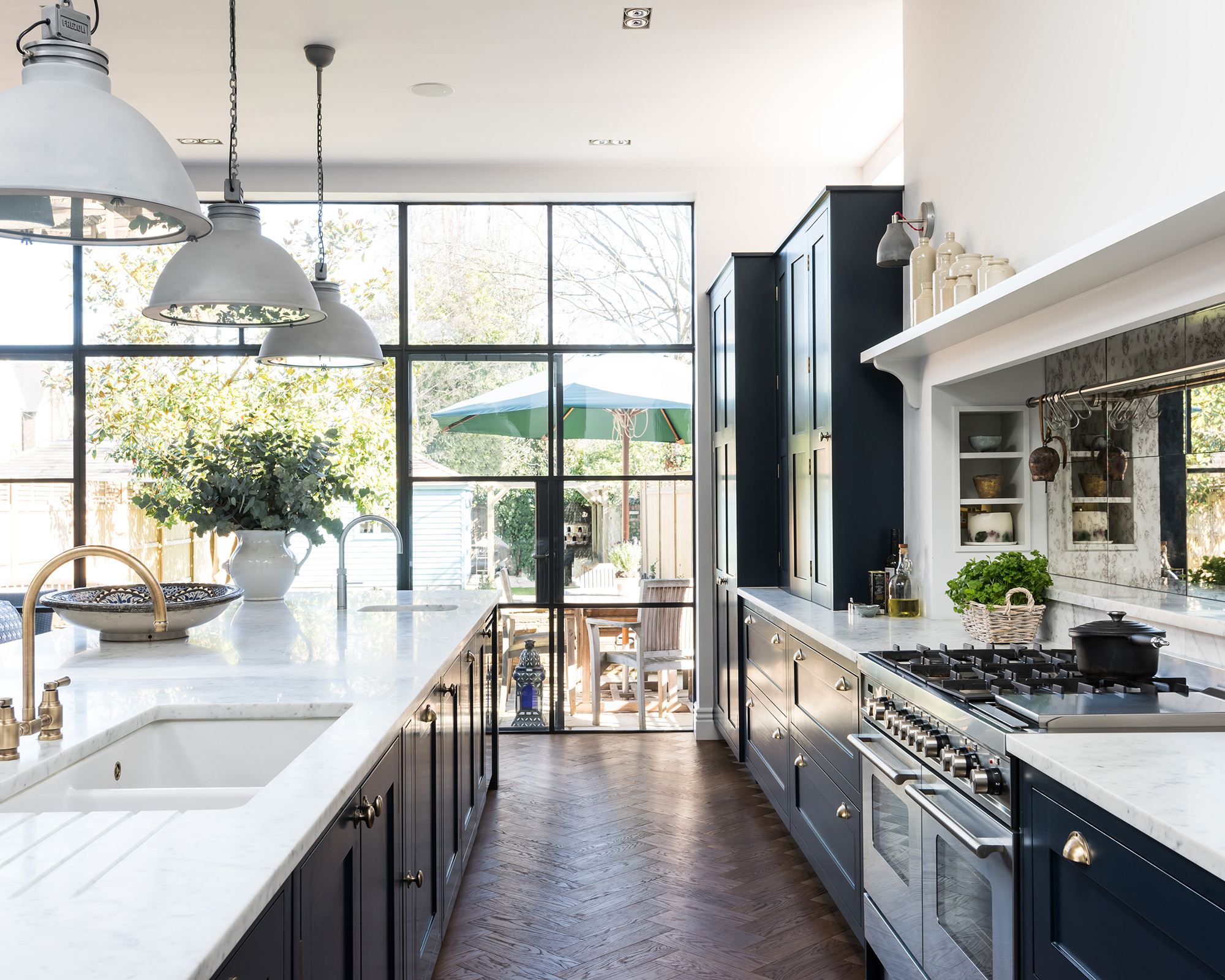An example of open plan kitchen ideas with large windows, marble counters and dark blue cabinetry.