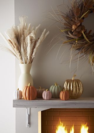 fall mantle with faux pumpkins, vase with dried flowers and autumnal wreath