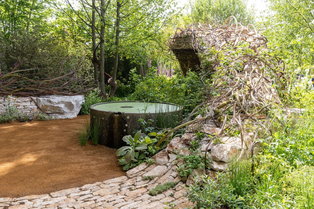 Images of the CPRE Show Garden On the Edge by Sarah Eberle. it focuses on grasses and flowers that grow around britain's edges, and is centred around a giant wooden carving of Gaia