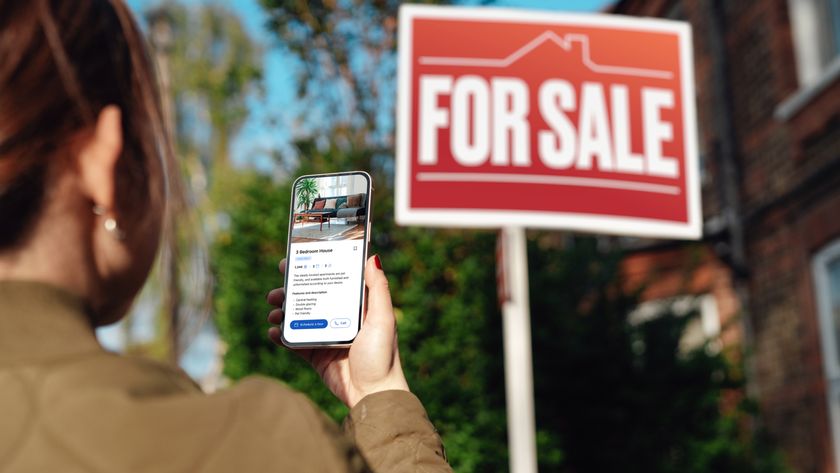 female looking at for sale sign holding up phone in hand