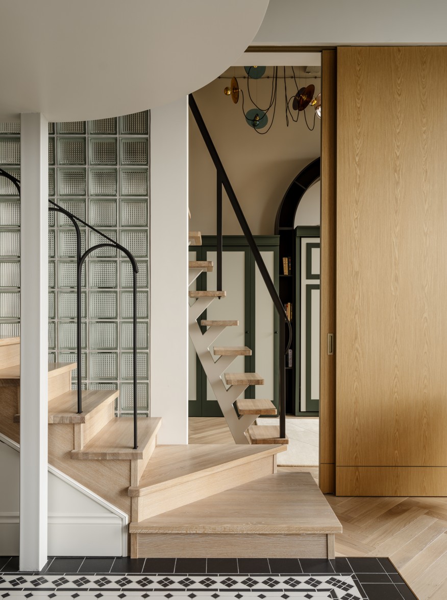 A curved wooden staircase with a wall made of glass blocks in the background