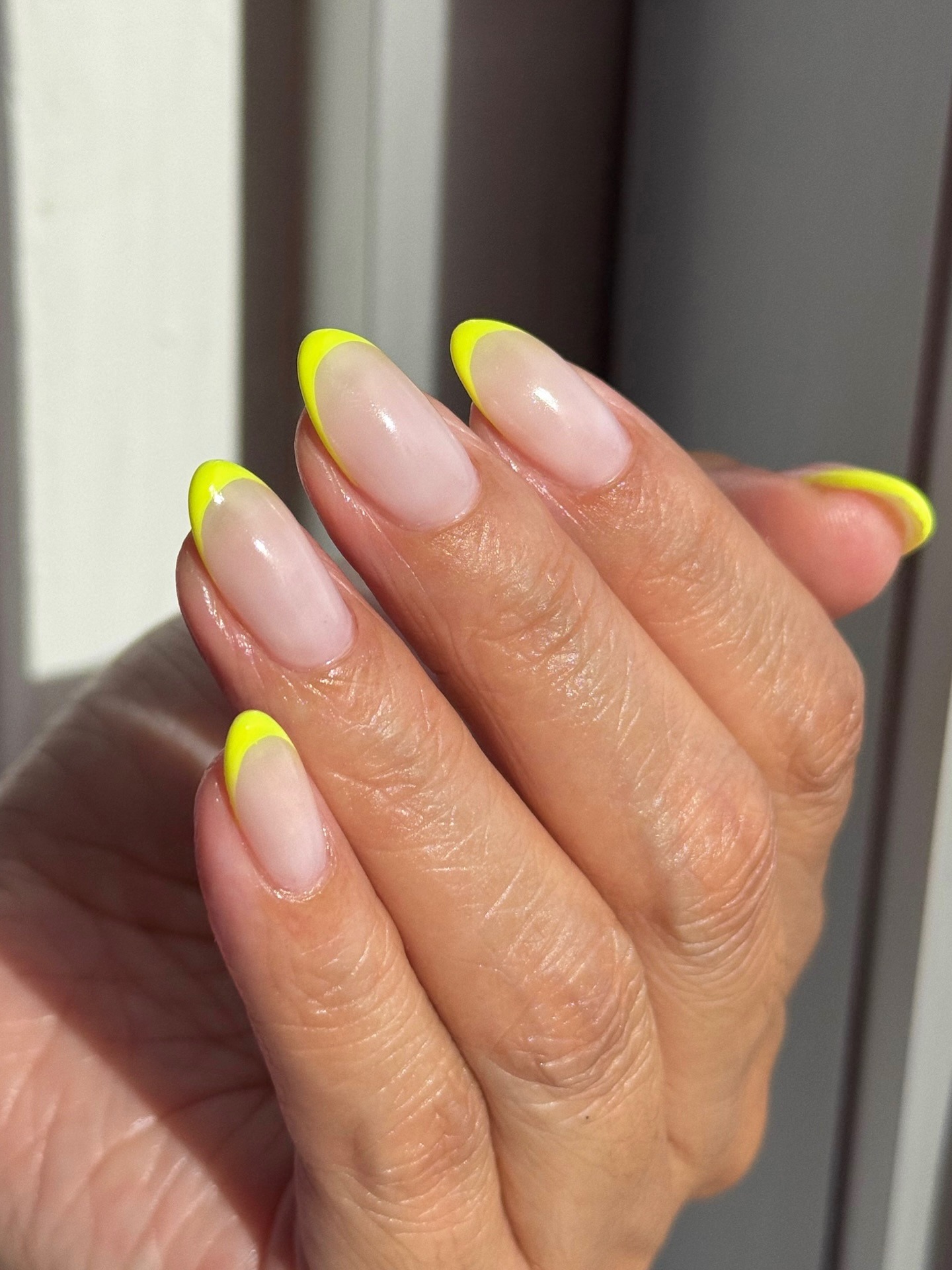 A neon yellow, almond-shaped French tip manicure
