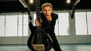Mike Dirnt poses in a publicity for the Mike Dirnt Epiphone Grabber Bass. The example he's holding has a Silverburst finish. 