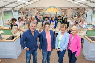 the great british baking show hosts stand in front of contestants at the kitchens