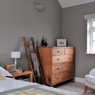 bedroom with grey wall and wooden drawers