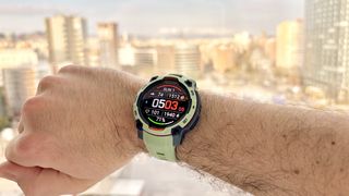 Close-up of the Garmin Instinct 3 on the writer's wrist with the Barcelona skyline out of focus in the distance