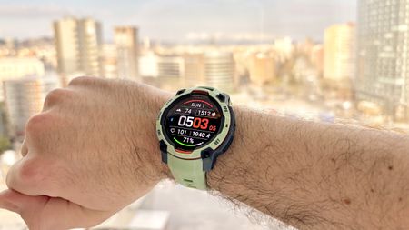 Close-up of the Garmin Instinct 3 on the writer's wrist with the Barcelona skyline out of focus in the distance