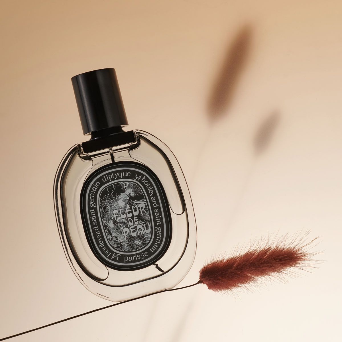 Diptyque Fleur de Peau Eau de Parfum floral perfume shot on a the stem of a dried flower