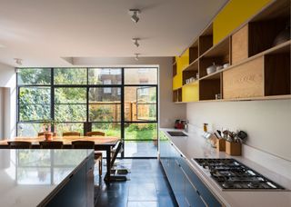 Open shelving with fronted cabinets in a modern kitchen in London. A dining table is also placed within the space with a large kitchen island.