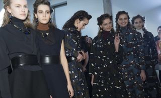 a line of six female models wearing dark coloured clothing