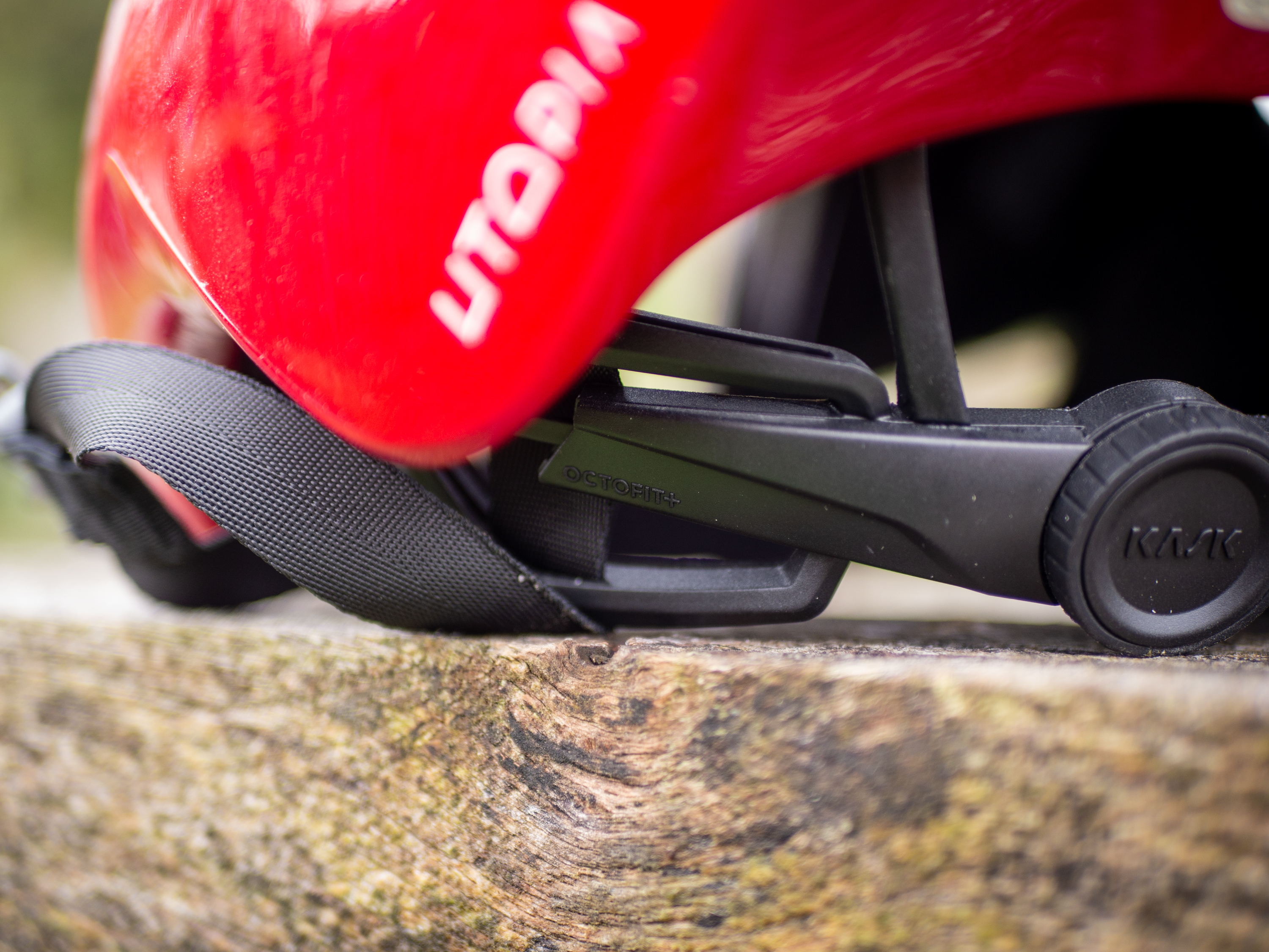 A red Kask Utopia Y aero helmet sits on a wooden bench