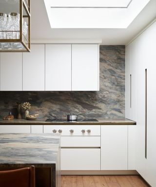 White kitchen with metal pans over stove, skylights, and turquoise countertops and backsplash