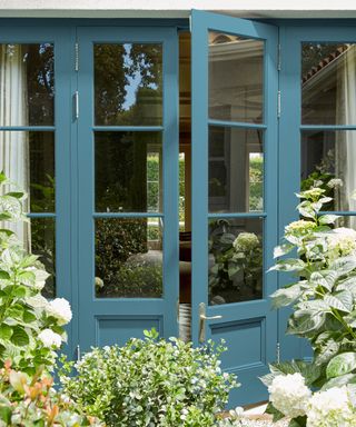 Mid blue painted glazed doors at the rear of a house with garden in bloom