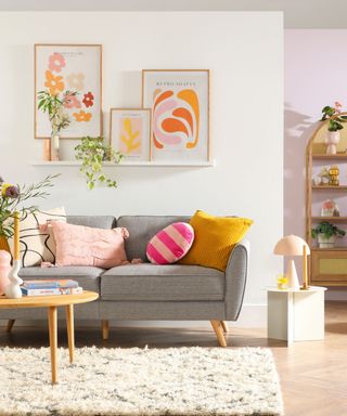 A small living room with a gray couch, bookshelf, and wall art