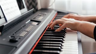Woman's hands resting on the keys of a music keyboard