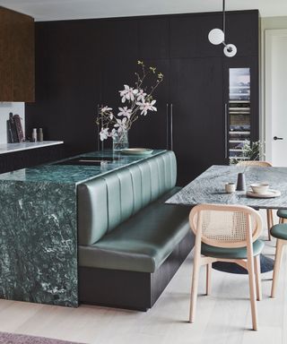 A smart kitchen with green marble for the worktops and leather banquet seating