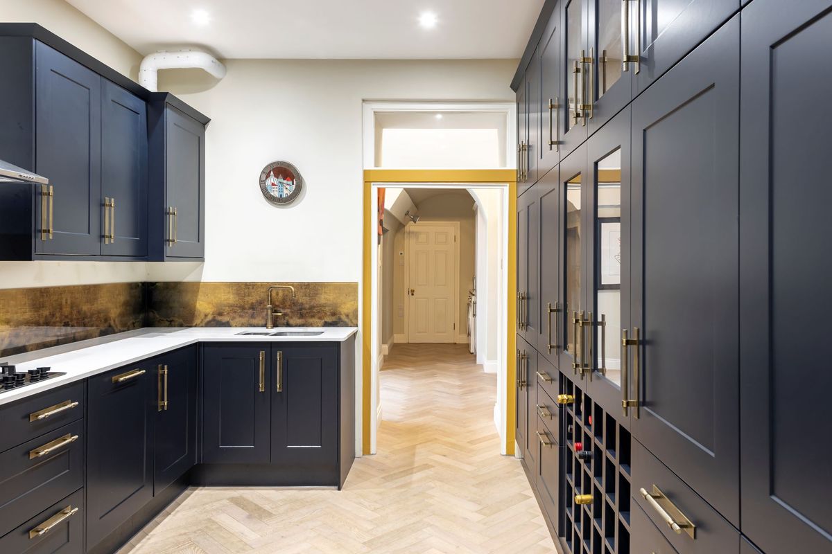 A blue kitchen with wooden herringbone floor