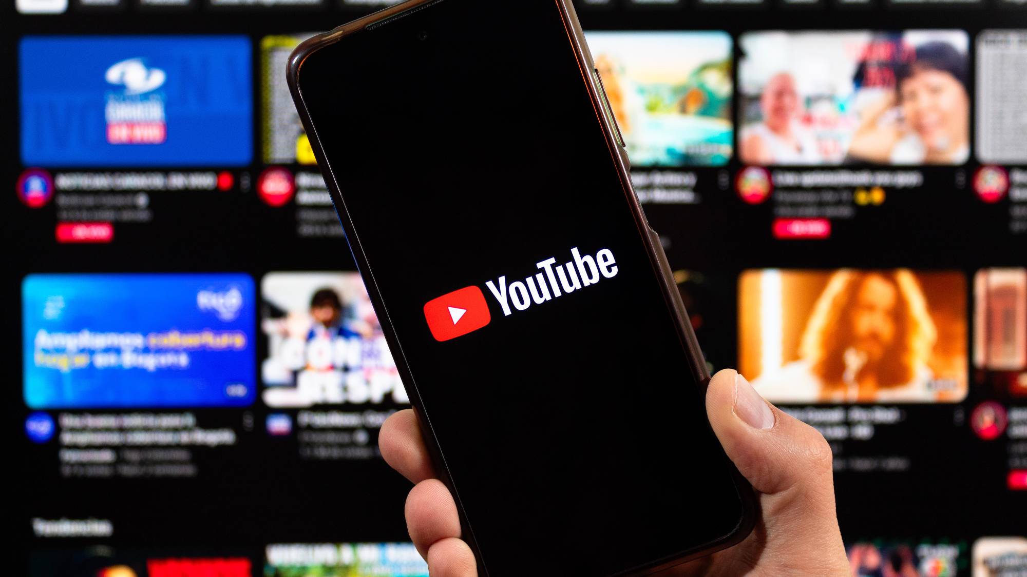 A smartphone with youtube logo and blurred youtube interface at background