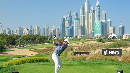 Rory McIlroy drives off the 8th hole at Emirates GC with the Dubai skyline in view