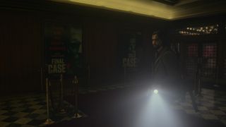 Alan Wake 2 Screenshot showing Alan in a movie theater holding a torch in the darkness