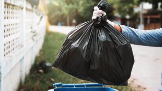 Man throwing out trash in black bag