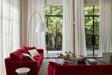 A living room with red sofas and long, white puddling curtains